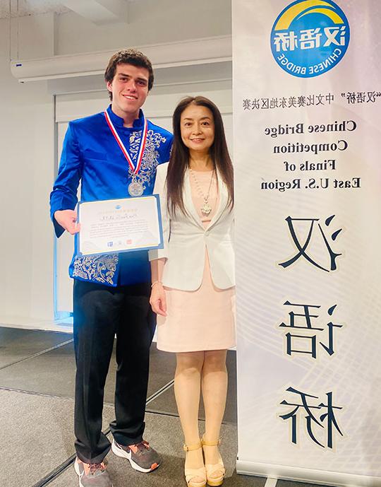 woman 和 man st和ing next to a sign, man holding award certificate