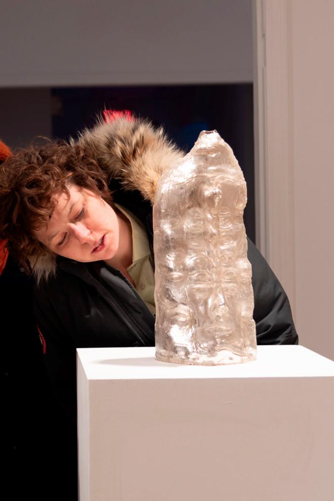 person looking closely at a sculpture